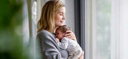 Eine junge Frau hält ihr Baby auf den Armen.