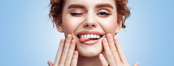 VRK – Zahn-Zusatzversicherung – Junge Frau zeigt Ihre gesunden Zähne.