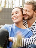 Junges glückliches Paar sitzt entspannt auf Balkon.