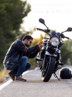 VRK Motorradversicherung - Ein Mann hockt neben seinem Motorrad