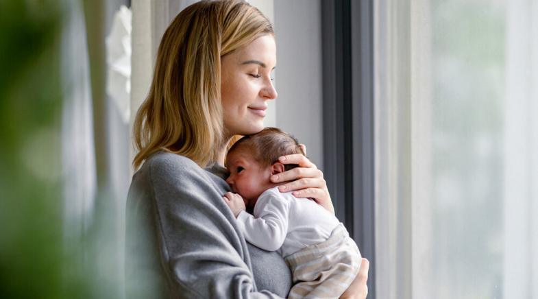 Eine junge Frau hält ihr Baby auf den Armen.