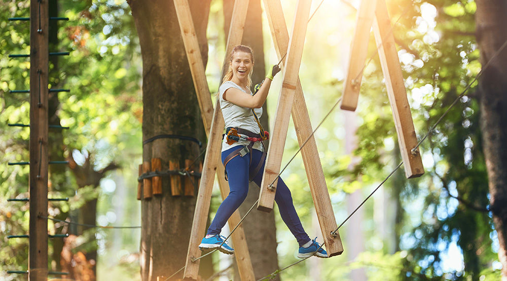 VRK Unfallversicherung Classic – Junge Frau im Outdoor-Kletterpark.