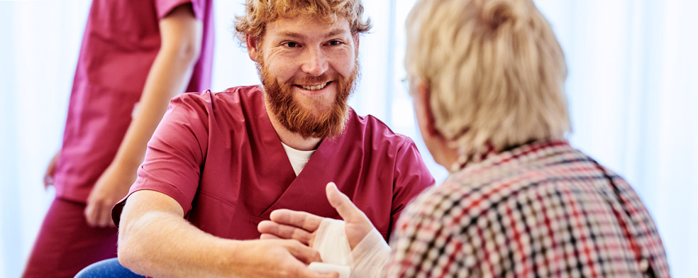 Ein männlicher Pfleger verbindet einen Patienten