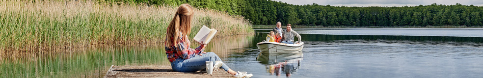 Eine Frau sitzt am See und liest ein Buch